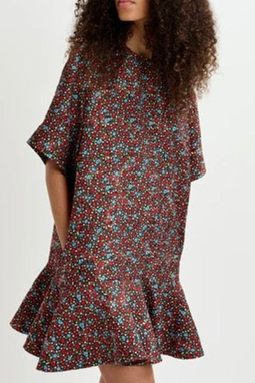 Woman wearing a floral dress and cap on a white background