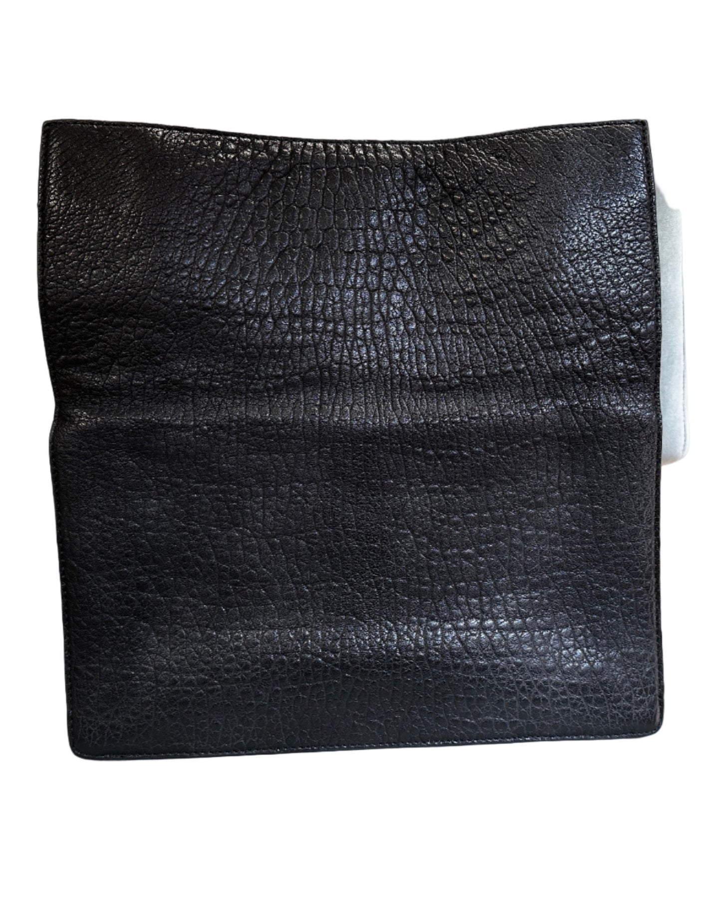 Black textured square object on a gray chair with a brick wall background