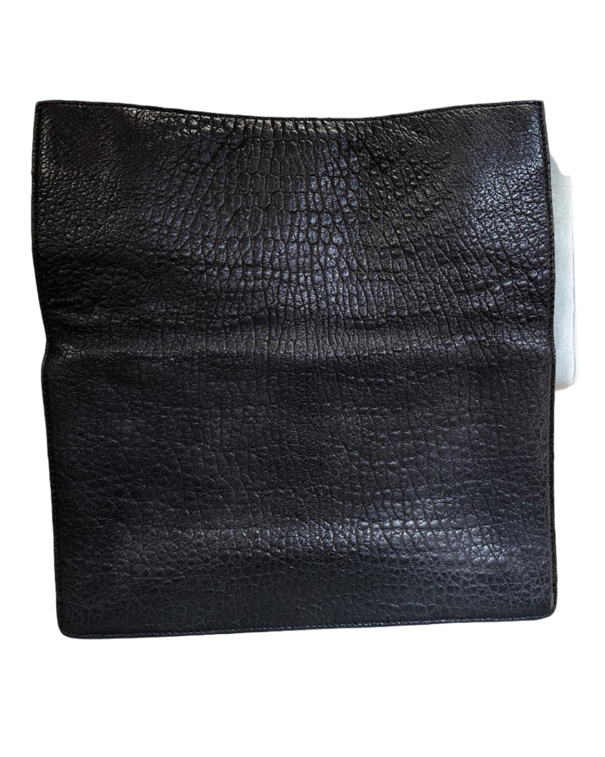 Black textured square object on a gray chair with a brick wall background