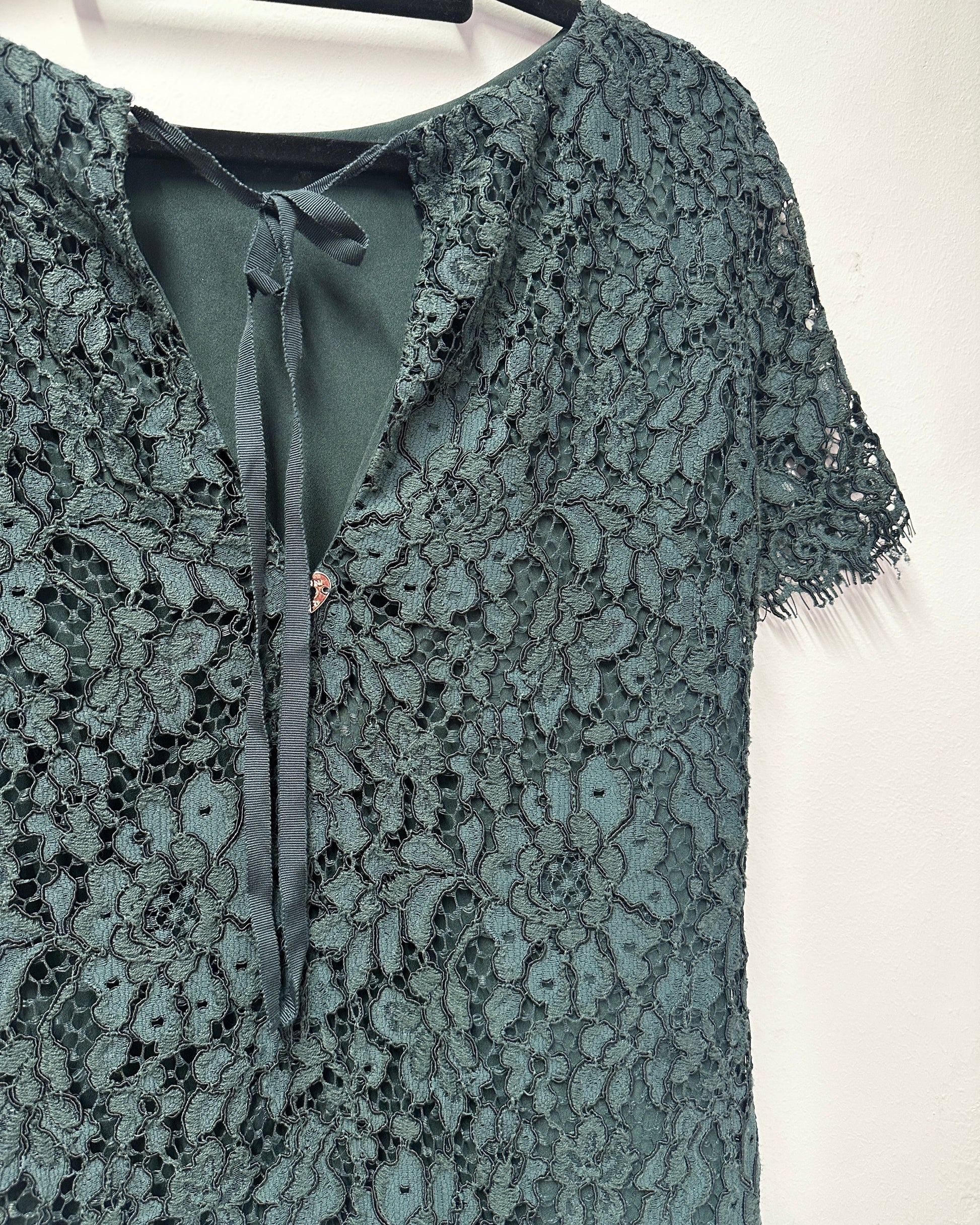 Green lace fabric with a close-up of the pattern on a white background