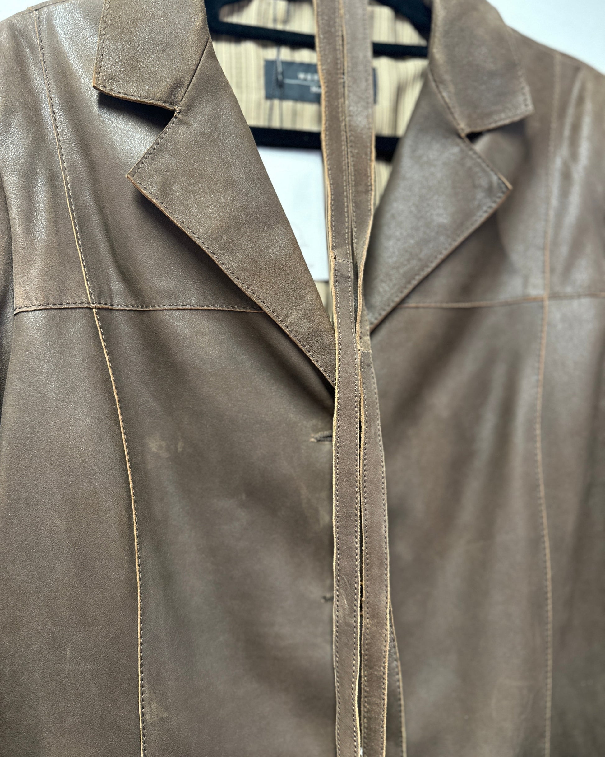 Brown leather jacket on a hanger with a white background